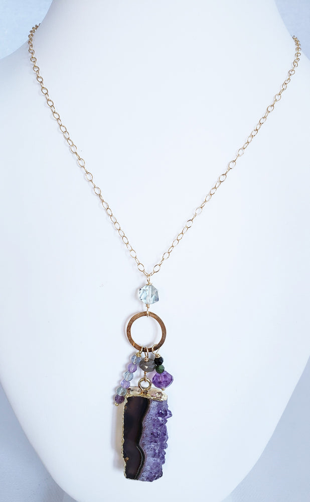 A Raw Amethyst Slice Forms A Charm Drop Pendant Necklace with Various Gemstones Of Fluorite, Green Tourmaline And Amethyst on 14 Kt. Gold-Filled Chain.
