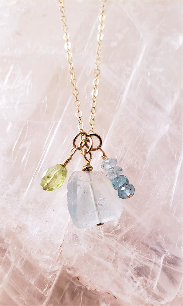 Aquamarine Faceted Gemstone is Surrounded by Peridot and Apatite Faceted Gemstones to Form a Cluster of Sparkle.